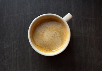 Cup of coffee on a wooden table close up. Kind from above.