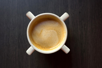 Cup of coffee with four pens by close-up on a wooden background. Top view