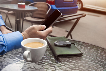 Cup of coffee and hand of man with a cellular telephone for Your advertisement text message.