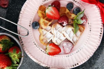 Traditional belgian waffles with fresh fruit and powder sugar on wooden board