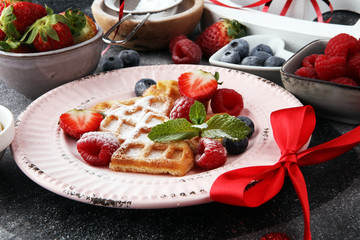 Traditional belgian waffles with fresh fruit and powder sugar on wooden board