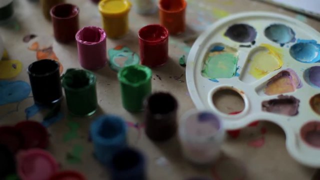 jars of paint, the girl takes a tube with paint