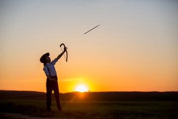 Silhouette of child playing with bow and arrows, archery shoots a bow at the target.