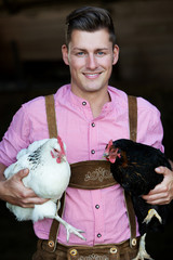 young bavarian man holding two chickens