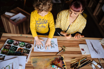 Young mother and her son playing with color paints in art studio.