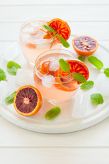 Blood orange cocktail with slices of orange on white wooden background