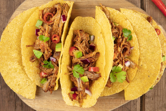 Closeup of Mexican tacos with pulled meat, avocado, chili peppers, cilantro