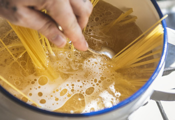 A chef boiling capellini pasta in the pot