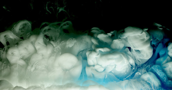 Blue and white acrylic paint cloud spraying in water on black background.