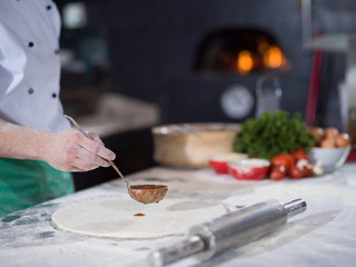 Chef smearing pizza dough with ketchup