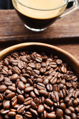 Close up of cup of coffee and coffee bean in wooden bowl
