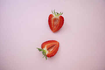 Two halves of strawberry on pink background.