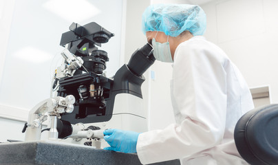 Woman doctor working in medical lab with manipulator and microscope - obrazy, fototapety, plakaty