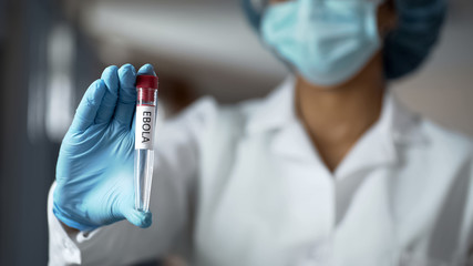 Scientist holding ebola vaccine liquid in test tube, biochemistry experiment © motortion