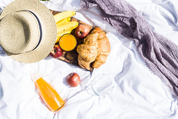 Summer picnic in the nature with croissants, juice and fruit on a white veil among the green grass. Leisure in nature
