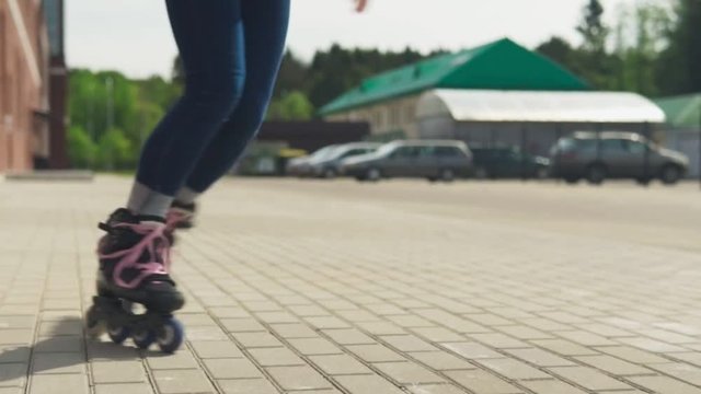 Women's legs riding on roller skates on city street