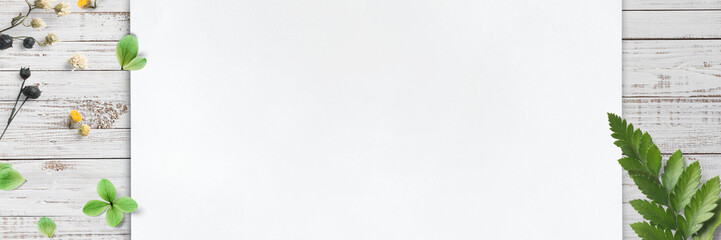 soft little flowers and leaves with paper sheet on rustic wooden board