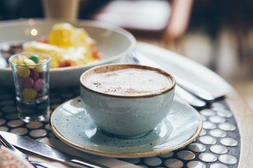 Close-up of cup of coffee and breakfasts  eggs Benedict on the table in a modern cafe. Selective focus