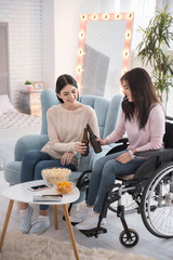 Cheers darling. Gay sister and immobile woman enjoying beer and talking
