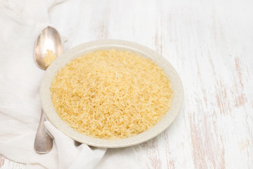 uncooked rice on plate on wooden background