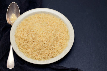 uncooked rice on plate on wooden background