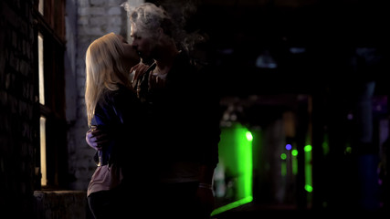 Drunk couple smoking and kissing passionately near night club, bad habits