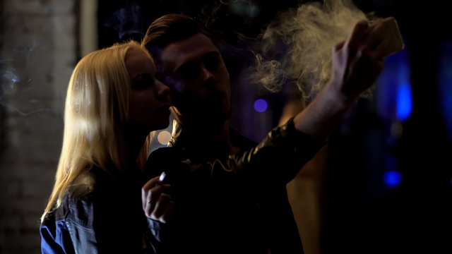 Handsome man taking selfie with woman smoking cigarette, acquaintance, flirt - Powered by Adobe