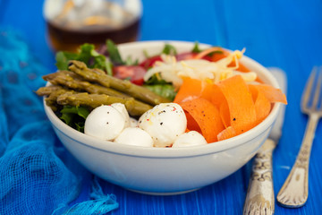 vegetables with cheese in small bowl on blue wooden background