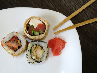 Sushi roll assorti and ginger in white plate with chopsticks on the  wooden table. Traditional japanese food
