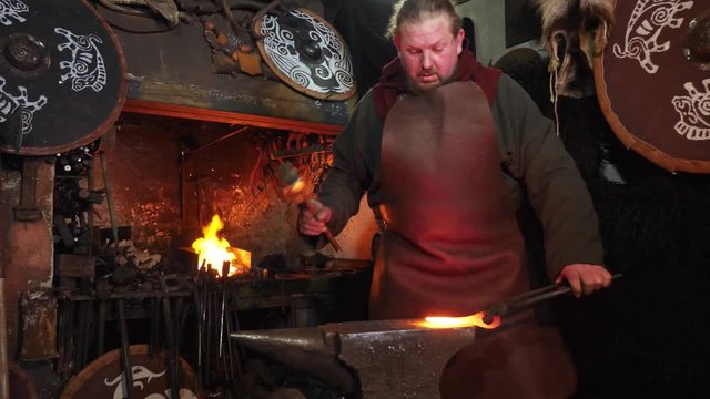 The hands of smith beat on glowing hot metal and sparks fly in all directions