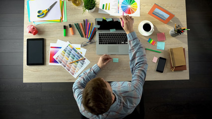 Male creator writing down his goals and plans on stickers and putting to laptop © motortion
