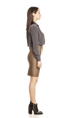 Profile of young businesswoman in skirt, shirt and boots standing on white background