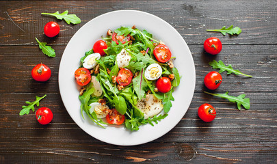Fresh salad with tomatoes, mixed greens ,nuts, eggs, on wooden background . Healthy food.