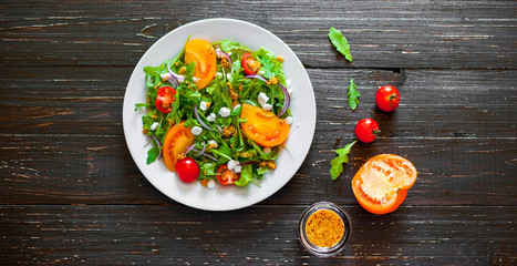 Fresh salad with tomatoes, mixed greens ,nuts, eggs, on wooden background . Healthy food.
