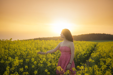 Fototapeta premium Woman in a rapeseed field at sunset