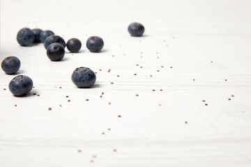 close up view of sweet blueberries and chia seeds on white tabletop