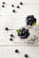 Naklejka na ściany i meble close up view of chia puddings with fresh blueberries and mint on white wooden tabletop