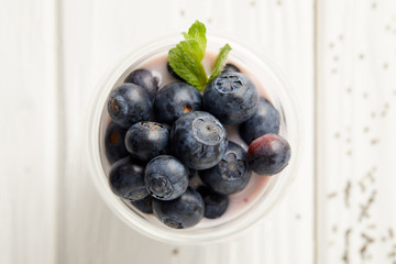 Top view of pudding with blueberries and mint on white wooden surface