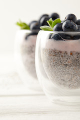 selective focus of chia puddings with fresh blueberries and mint on surface