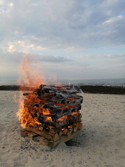 In Brand gesetzter Holzstapel am Sandstrand im Ostseebad Binz am Abend auf der Insel Rügen an der...