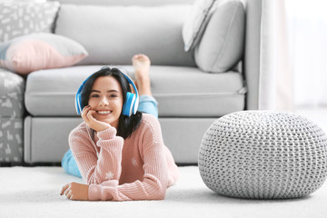 Young woman listening to music through headphones at home