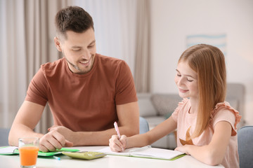 Cute little girl doing homework with father