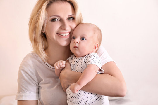 Young mother and her baby on light background