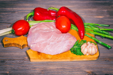 Fresh raw veal meat with vegetables on wooden background