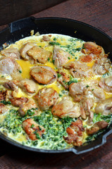 Chicken in spinach sauce in a pan on wooden background