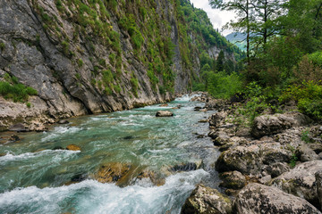 Fototapeta na wymiar The mountain river flows among the rocks in the mountain gorge in Georgia