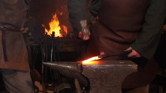 Blacksmiths has an effort on glowing hot metal and sparks fly in all directions.