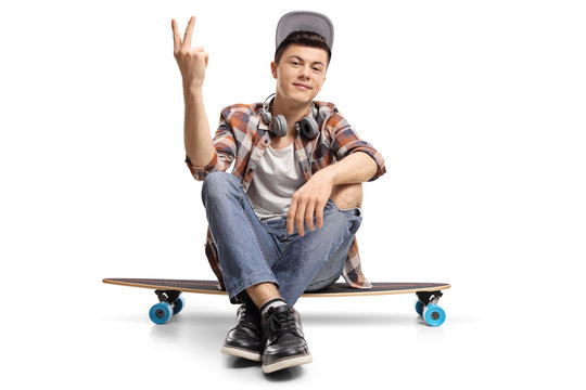 Teenage skater sitting on a longboard and making a peace gesture