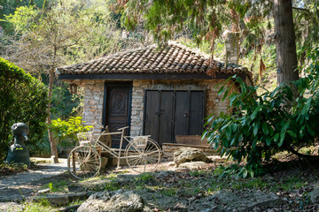 Stone house with a retro white wheel in front. A beautiful forest around the house