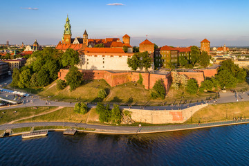Royal Wawel Cathedral and castle in Krakow, Poland. Aerial view in sunset light. Vistula River, riverbank with park. promenade and  walking people. Old city and Kazimierz district in the background